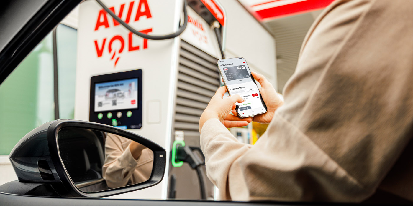 Frau mit Handy an Ladesäule